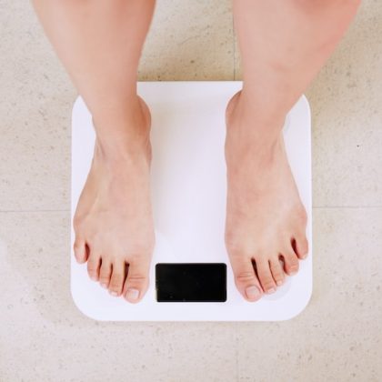 A woman stands on some weighing scales