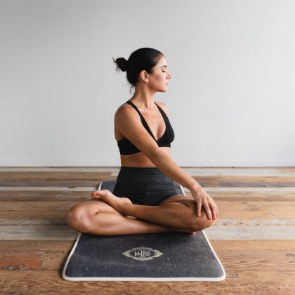 A woman sits in a cross-legged yoga pose with her eyes closed