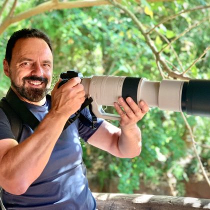 Dr Sam Fazio holds a professional camera and smiles at the camera