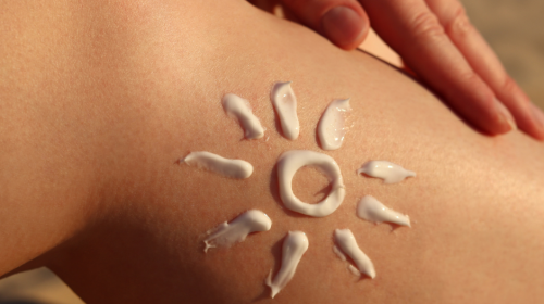 A leg with suncream on it in the shape of a sun.