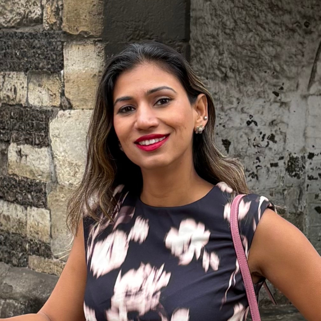 Dr Vibha Chaudhary smiles at the camera. She is wearing a black and white patterned dress