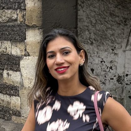 Dr Vibha Chaudhary smiles at the camera. She is wearing a black and white patterned dress